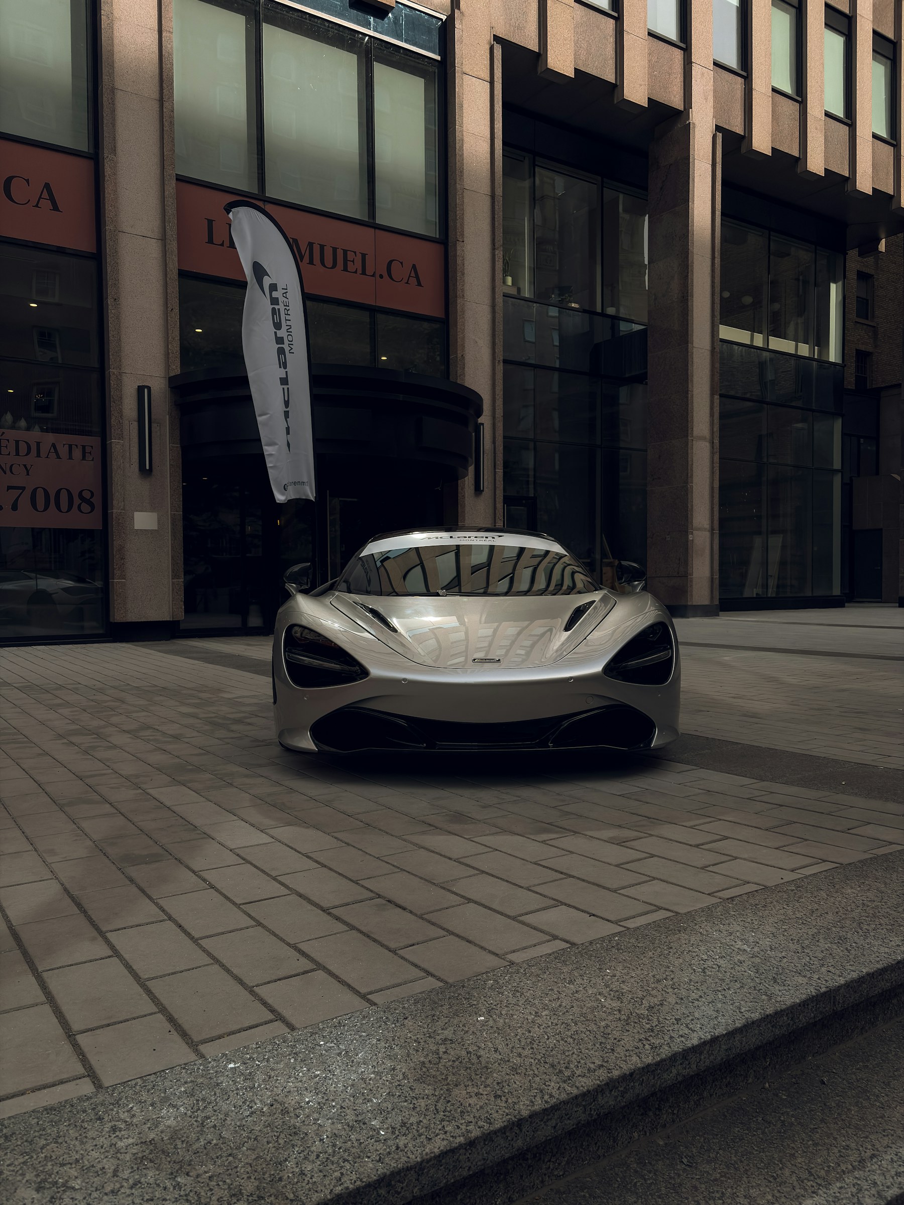 Silver McLaren sports car photographed outside a modern building